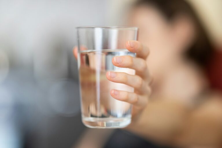 Eine Hand hält ein Glas Wasser