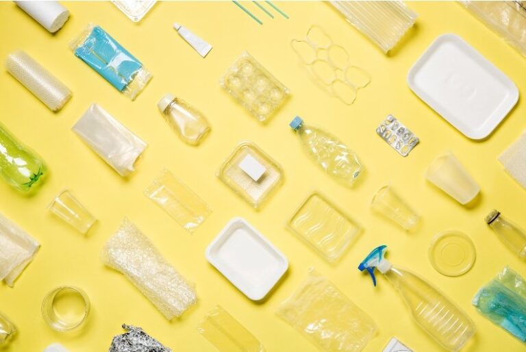 Verschiedene leere Plastikverpackungen auf gelbem Untergrund arrangiert