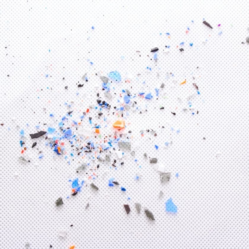 Bunte kleine Plastikstücke (Mikroplastik) auf weißem Untergrund